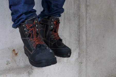 Foto de Un trabajador de la construcción lleva botas de cuero marrón que se ve muy fresco y de moda - Imagen libre de derechos