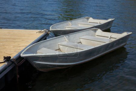 two rowboats on the edge of a dock on a calm lake aluminum boats