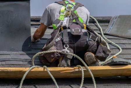 Téléchargez les photos : Professionnel réparation travailleur de la construction homme couvreur travaillant sur la sécurité de l'entretien du toit avec corde sécurisée - en image libre de droit