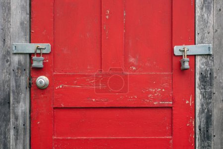 Vintage red door with weathered wood, crackling paint, and padlock symbolizing security and privacy. Forbidden entry.