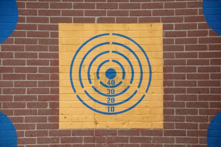 A target painted on a brick wall symbolizes strategic planning and focused effort, aiming for business success and achieving goals amidst challenges.