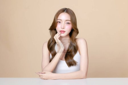 Photo for Young Asian beauty woman curly long hair with korean makeup style touch her face and perfect skin on isolated beige background. Facial treatment, Cosmetology, plastic surgery. - Royalty Free Image