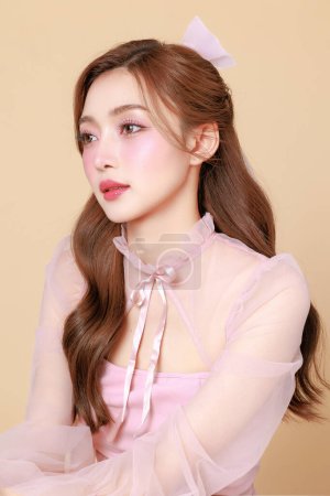 Photo for Young cute Asian woman in a pink elegant dress, Korean style makeup, moisturized, smooth, perfect skin on a beige background. Facial treatment, Cosmetology, plastic surgery. - Royalty Free Image