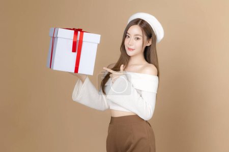 Photo for Young Asian beauty woman long hair with beret lovely face and perfect clean skin on isolated beige background. Female model holding gift boxes, Facial treatment, Cosmetology, plastic surgery. - Royalty Free Image