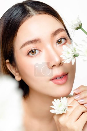 Photo for Close up of Asian woman with a beautiful face and fresh, smooth skin and flower. Cute female model with natural makeup and sparkling eyes is looking at the camera on white isolated background. - Royalty Free Image