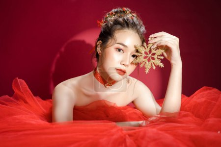 Photo for Young Asian pretty woman model in a posh stylish luxury red dress on a red background isolated. Beautiful confident female posing and look at camera. - Royalty Free Image