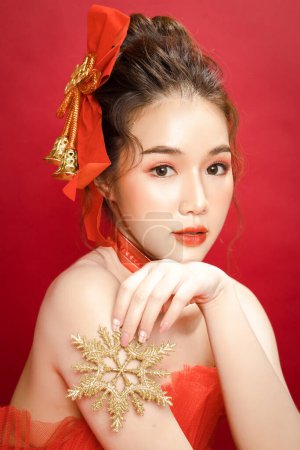 Young Asian pretty woman model in a posh stylish luxury red dress on a red background isolated. Beautiful confident female posing and look at camera.