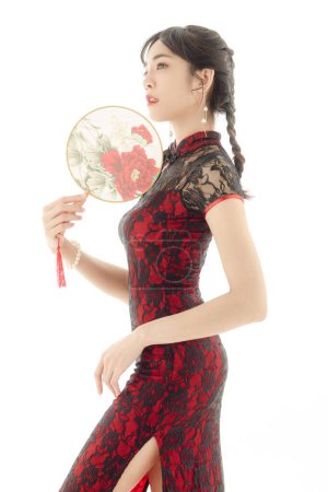 Foto de Feliz año nuevo chino. Mujer asiática con vestido moderno cheongsam qipao sosteniendo un ventilador sobre fondo blanco aislado. Lindo modelo femenino. - Imagen libre de derechos