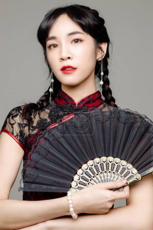 Photo for Happy Chinese new year. Asian woman wearing modern cheongsam qipao dress holding a fan on isolated background. Cute female model. - Royalty Free Image