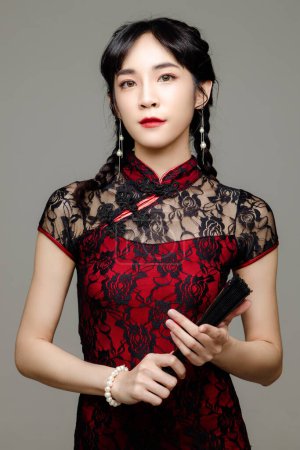 Foto de Feliz año nuevo chino. Mujer asiática vistiendo moderno cheongsam qipao vestido sosteniendo un ventilador sobre fondo aislado. Lindo modelo femenino. - Imagen libre de derechos