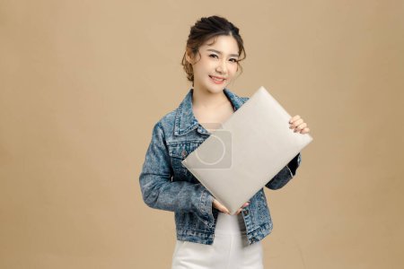 Téléchargez les photos : Sourire belle femme asiatique tenant un panneau blanc vierge sur fond beige isolé.. regarder la caméra, espace de copie. - en image libre de droit