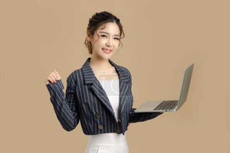 Photo for Smile beautiful Asian business woman holding tablet and raising arms congratulation her success on Isolated beige background. look at camera, copy space. - Royalty Free Image