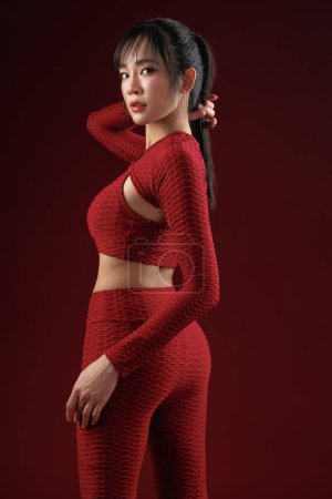 Photo for Energetic Asian fit slim good shape body building athletic woman in red sportwear workout indoor studio. Young strong female model aerobic training stretching, skin care, wellness, Health insurance. - Royalty Free Image