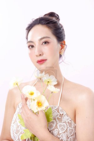 Photo for Beautiful young Asian woman model bun hair with natural makeup on face clean fresh skin holding flower on isolated white background. Cute girl portrait, Facial treatment, Body care, Beauty and Spa. - Royalty Free Image