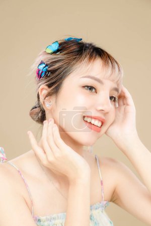 Photo for Asian woman with a beautiful face and Perfect clean fresh skin. Portrait of female model with Butterfly and sparkling eyes on beige isolated background. Cosmetology, Body care, plastic surgery. - Royalty Free Image