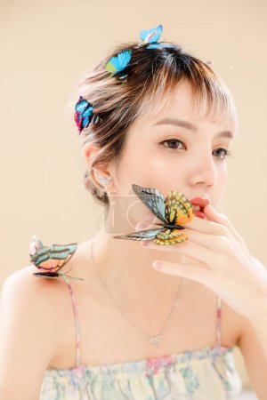 Photo for Asian woman with a beautiful face and Perfect clean fresh skin. Portrait of female model with Butterfly and sparkling eyes on beige isolated background. Cosmetology, Body care, plastic surgery. - Royalty Free Image