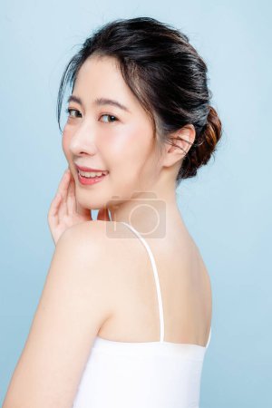 Photo for Beautiful Asian woman with perfect clear fresh skin. Happy girl model with fresh glowing hydrated facial and natural makeup on blue background. Cosmetology, beauty and spa, wellness, Plastic surgery. - Royalty Free Image