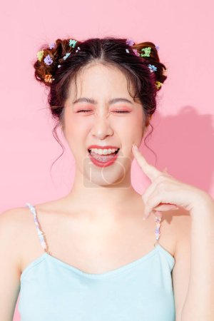 Foto de Retrato de hermosa joven asiática feliz mujer en azul lindo vestido de moda usar gafas de sol sonriendo y posando en el fondo de color rosa pastel aislado espacio vacío. - Imagen libre de derechos
