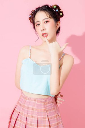 Foto de Retrato de hermosa joven asiática feliz mujer en azul lindo vestido de moda usar gafas de sol sonriendo y posando en el fondo de color rosa pastel aislado espacio vacío. - Imagen libre de derechos