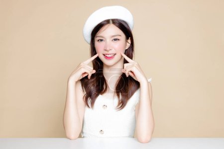 Photo for Cute Asian woman with perfect clear fresh skin. Pretty girl model wearing white beret and natural makeup on beige background. Cosmetology, beauty and spa, wellness, Plastic surgery. - Royalty Free Image