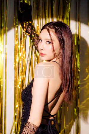 Téléchargez les photos : Jeune charmante belle femme asiatique portant robe noire sexy mode profiter de célébrer la fête posant avec des boîtes-cadeaux de luxe sur fond brillant paillettes d'or avec des ballons. anniversaire, Nouvel an concept. - en image libre de droit