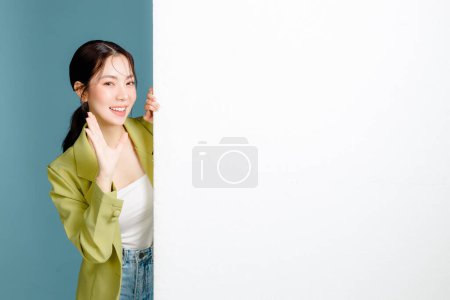 Téléchargez les photos : Jeune femme d'affaires souriante heureux succès employé 20s en veste verte décontractée jetant un coup d'oeil annoncer tableau blanc vierge isolé sur fond bleu pastel. Entrepreneurs féminins, concept d'employé de bureau. - en image libre de droit
