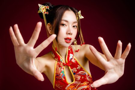 Photo for Beautiful Asian woman with clean fresh skin wearing cheongsam qipao posing on red background. Portrait of female model in studio. Happy Chinese new year. - Royalty Free Image