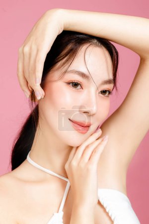 Photo for Young Asian woman gathered in ponytail with natural makeup on face have plump lips and clean fresh skin wearing white camisole on isolated pink background. Portrait of cute female model in studio. - Royalty Free Image