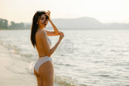 Photo for Portrait of gorgeous Asian woman model beauty skincare suntan posing sunbathing tanning in white one piece swimsuit relaxing at beach summer resort. Spa, wellness, laser. - Royalty Free Image