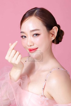 Photo for Beautiful young Asian woman model bun hair with natural makeup on face clean fresh skin on isolated pink background. Cute girl portrait, Facial treatment, Valentine concept. - Royalty Free Image
