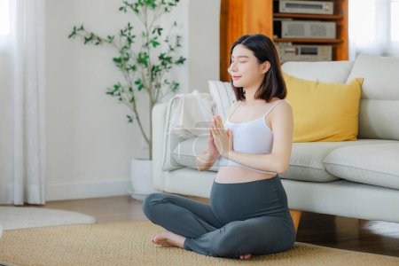 Photo for Young Asian happy pregnant woman is meditating while sitting in lotus position. Family plan, pregnancy, motherhood, people and expectation, Meditating on maternity concept - Royalty Free Image