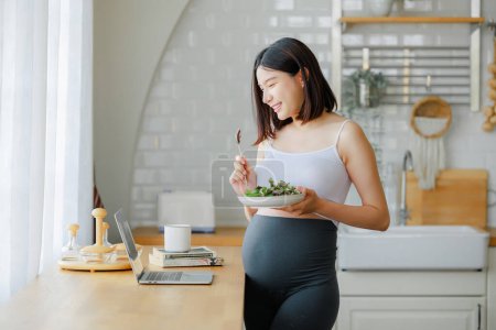 Téléchargez les photos : Grossesse, alimentation saine et concept de personnes - gros plan de la femme enceinte heureuse manger de la salade de légumes pour le petit déjeuner au lit à la maison. Concept de garde prénatale pour les enfants et la maternité. - en image libre de droit