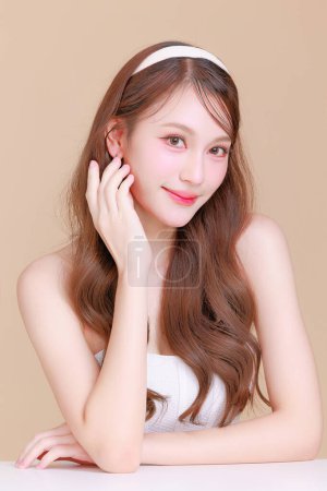 Photo for Pretty Asian beauty woman curly long hair with Korean makeup glowing face and healthy facial skin portrait smile on isolated beige background. Cosmetology ,Plastic surgery. - Royalty Free Image