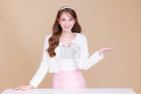 Téléchargez les photos : Jolie sourire jeune bureau asiatique entrepreneur d'affaires sourire montrant la paume des mains ouverte debout sur fond beige isolé. concept de publicité commerciale. - en image libre de droit