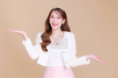 Photo for Pretty smiling young office Asian business entrepreneur smile showing open hand palm standing on isolated beige background. concept for commercial advertising. - Royalty Free Image