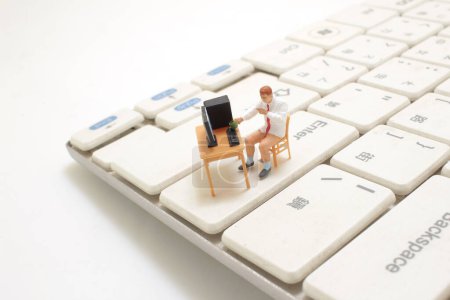 Téléchargez les photos : Une mini figure dans le bureau à domicile sur le clavier - en image libre de droit