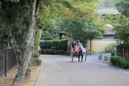 Photo for A rickshaw traveling along a narrow street in Arashiyama, Kyoto. 2 Nov 2013 - Royalty Free Image