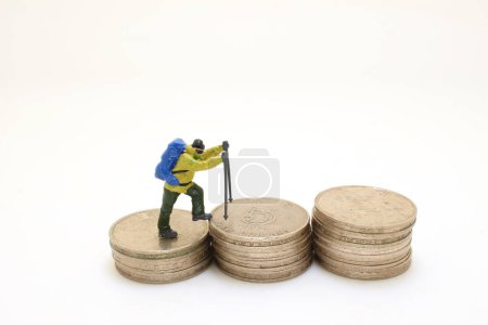 Hikers with backpacks figure with Stack of coins