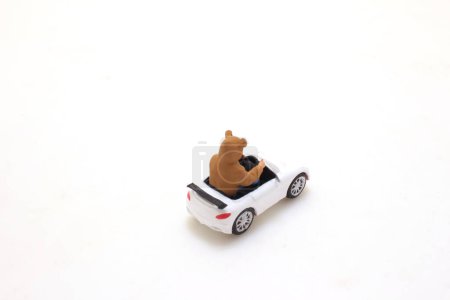 Téléchargez les photos : Un chien jouet conduisant une voiture blanche convertible sur blanc - en image libre de droit