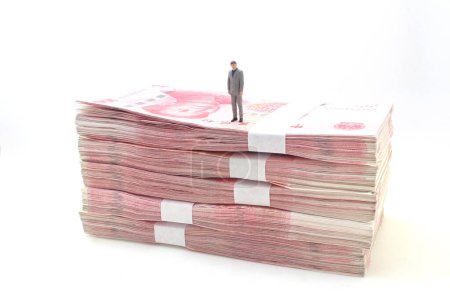 Foto de Hombre de negocios de pie en pilas de billetes de Yuan chino, - Imagen libre de derechos