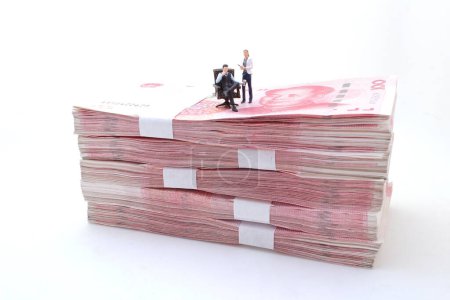 Foto de Hombres de negocios de pie en pilas de billetes de Yuan chino, - Imagen libre de derechos