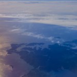 View from plane window. Clouds above water surface. Atmosphere concept