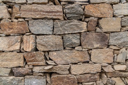 Tamaños, formas y colores mezclados de piedras de campo que forman una pared de roca en el pueblo indio del norte de Turtuk