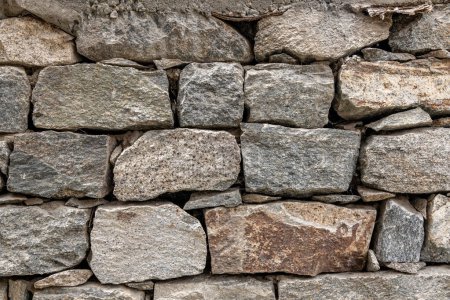 Foto de Tamaños, formas y colores mezclados de piedras de campo que forman una pared de roca en el pueblo indio del norte de Turtuk - Imagen libre de derechos