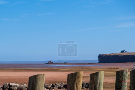 Panoramic view of low tide showing clear blue sky contrast with red sandy beach.