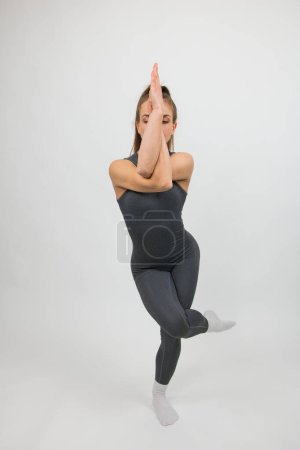A girl athlete does yoga, demonstrating the exercises. Studio shot.