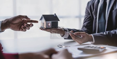 Photo for Real estate agent gives key to smiling clients. Happy couple signs papers and takes key to new home. Concept of young family making dream come true, buying house or getting apartment mortgage approval - Royalty Free Image