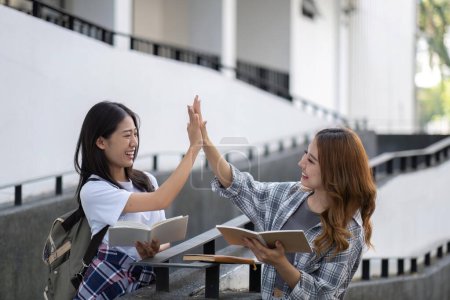 Téléchargez les photos : Joyeux collège asiatique deux étudiantes parlent, partagent des idées, travaillent ensemble sur leur projet scolaire. - en image libre de droit