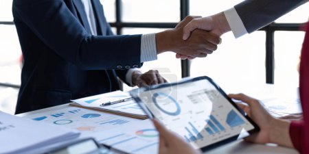 Foto de Shaking hand business leaders talk about charts, financial graphs showing results are analyzing and calculating planning strategies, business success building processes. - Imagen libre de derechos