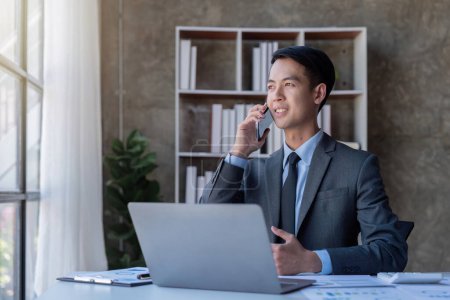 Téléchargez les photos : Homme d'affaires occupé comptable Asiatique mâle faisant appel au téléphone dans le bureau de travail, démarrage, rapport, fiscalité, comptabilité, statistiques, et concept de recherche analytique. - en image libre de droit